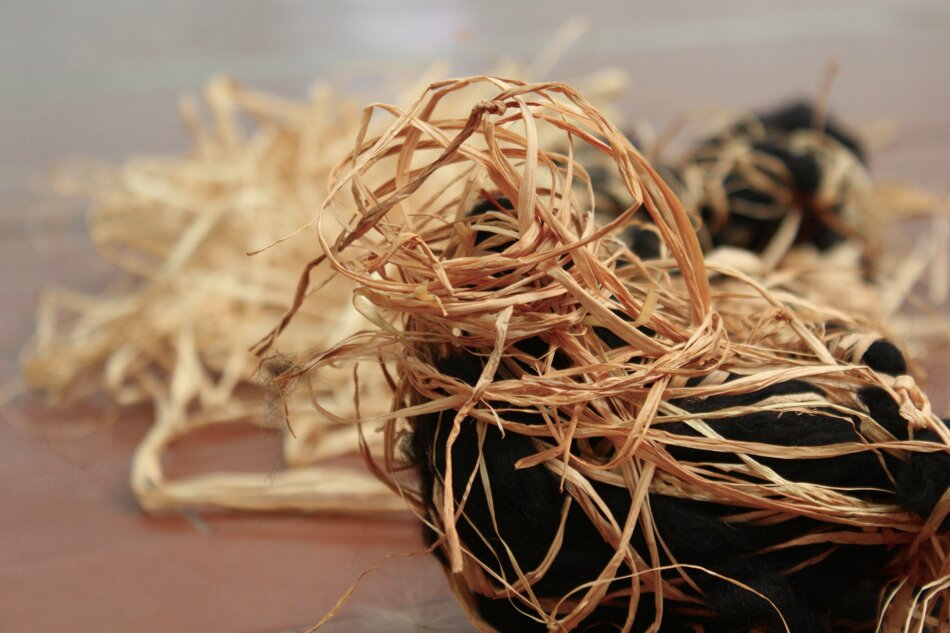 A close-up of a tangled mass of raffia and black yarn.