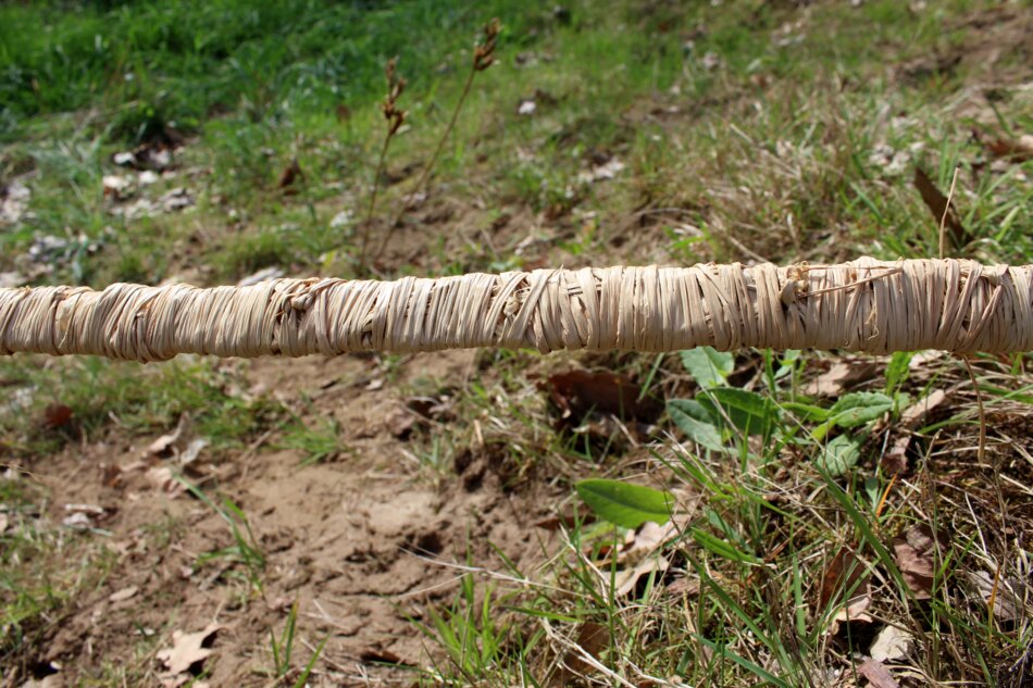 Close-up of a metal strip tightly wrapped with raffia.